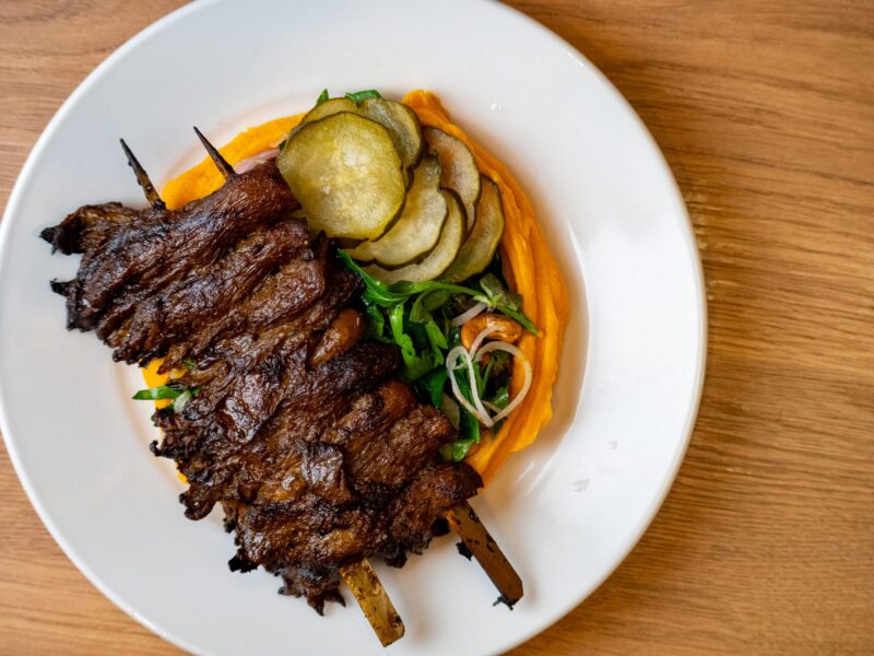 Birds-eye-view image of shiitake mushrooms on skewers with fried courgette and sweet potato mash at Folde Battersea restaurant