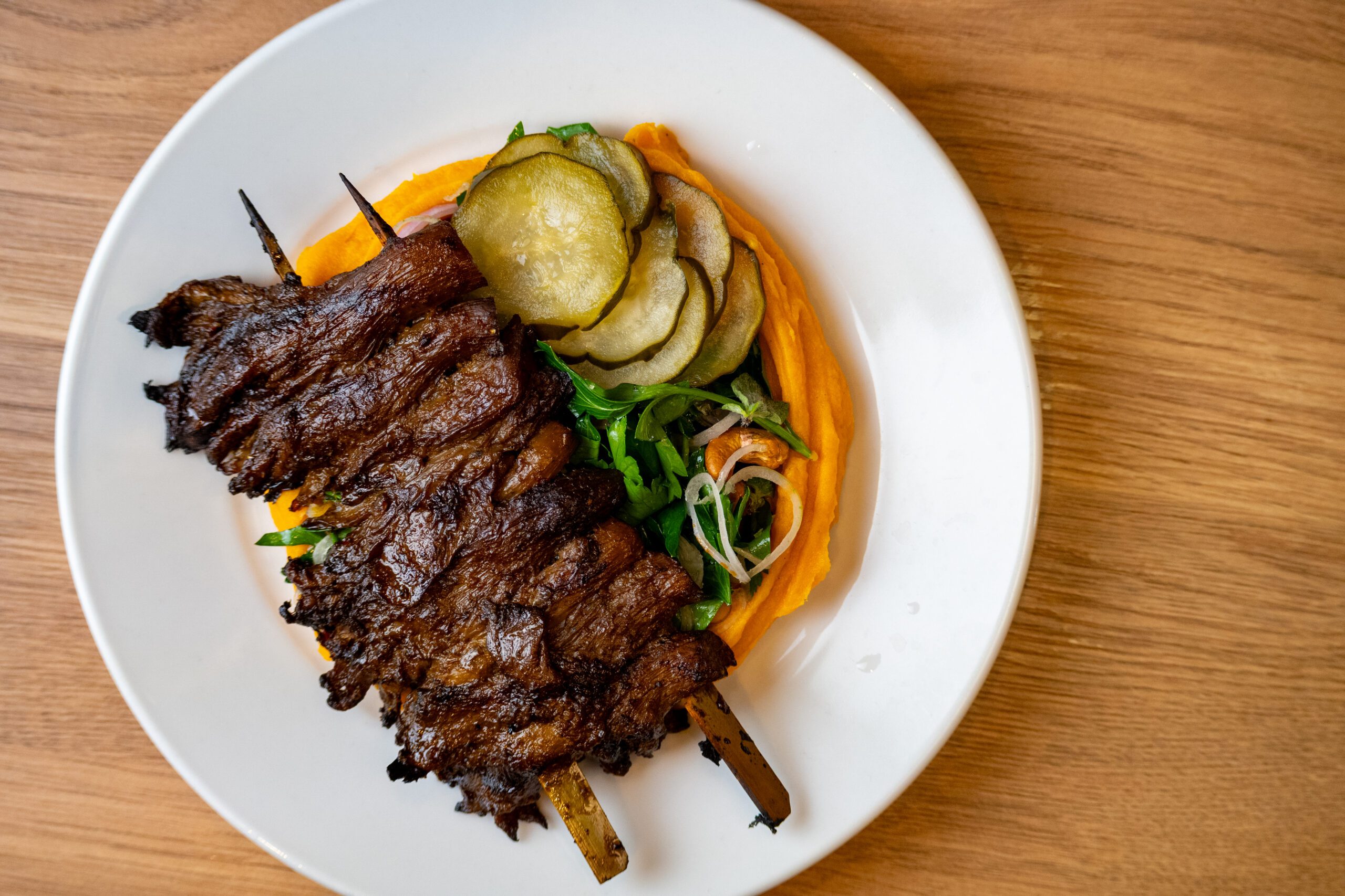 Birds-eye-view image of shiitake mushrooms on skewers with fried courgette and sweet potato mash at Folde Battersea restaurant